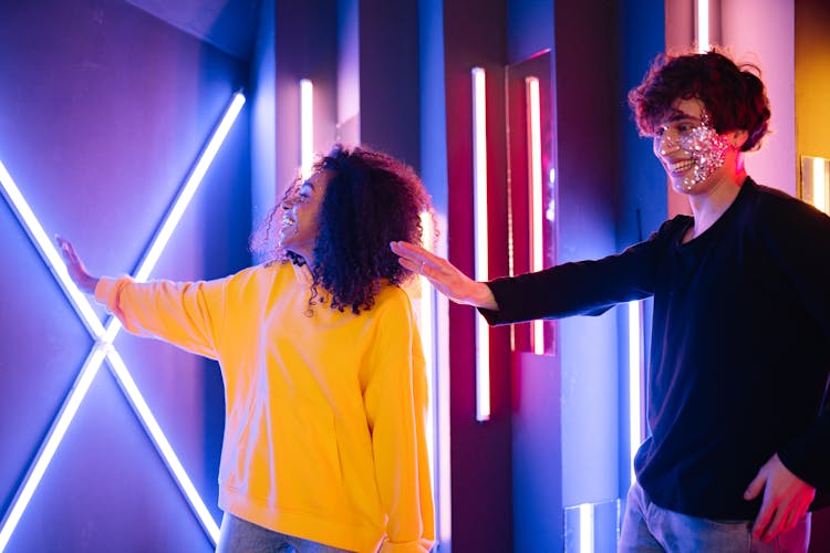 A Man And A Woman Wearing Long Sleeves Standing Near Neon Lights