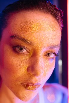 Close-up portrait of a young woman with glittery makeup in trendy fashion.