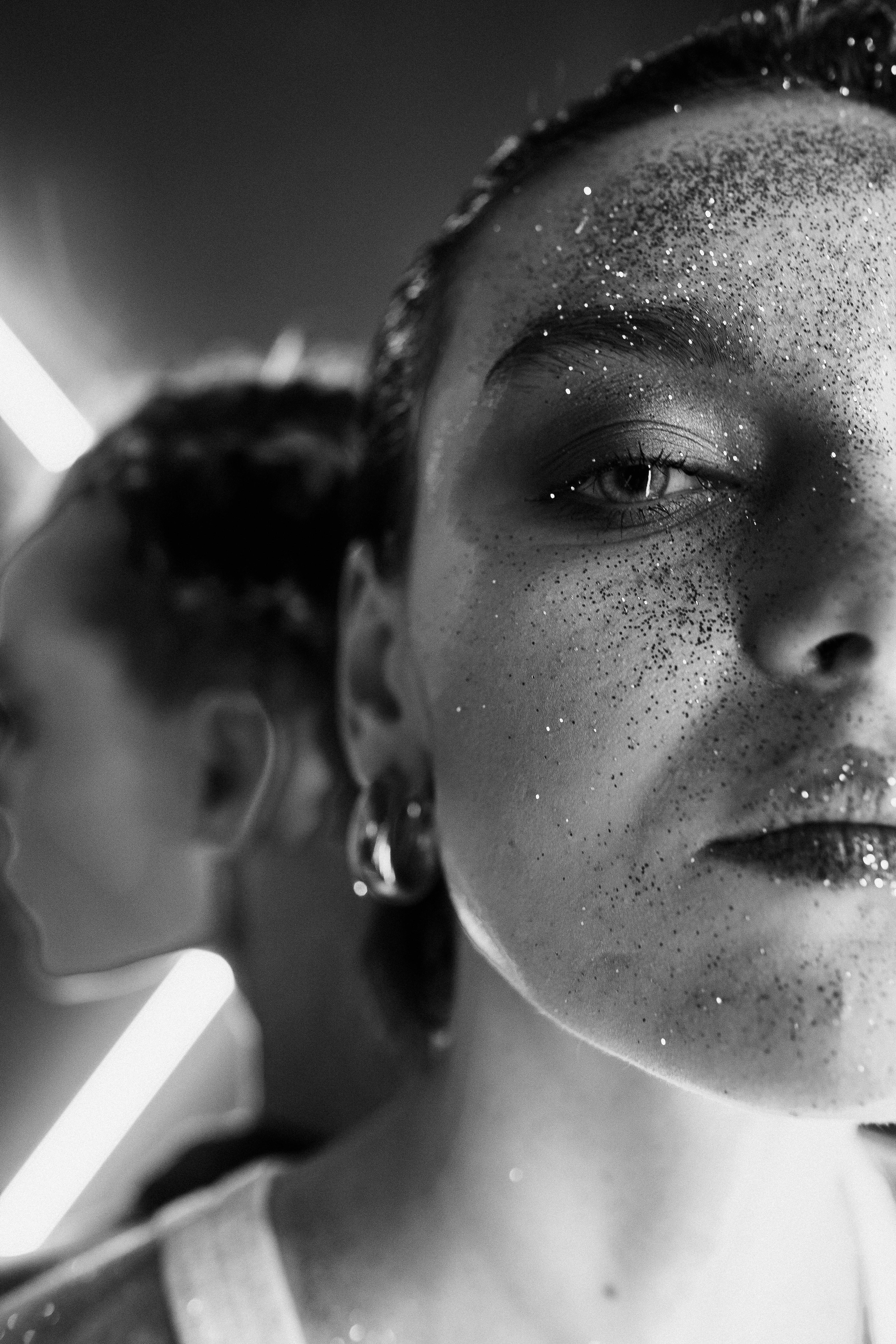 Creative black and white portrait of a woman adorned with glitter, featuring a striking half-face composition.