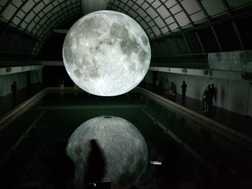 Photo De L'hologramme De La Lune Flottant Sur L'eau Près De Personnes à L'intérieur De La Pièce