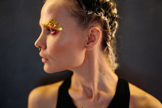 A striking profile portrait of a woman with braided hair and creative glitter makeup, showcasing a modern artistic style.