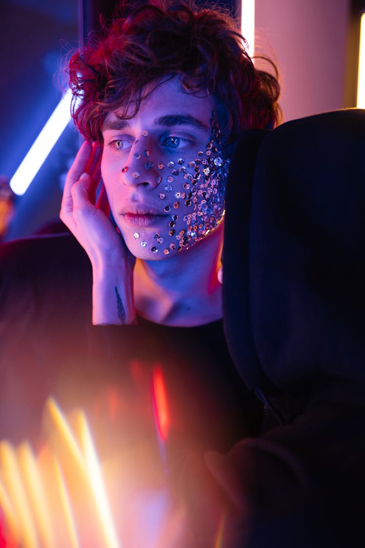 A Man Wearing Silver Glittery Makeup Standing Near Neon Lights