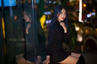 Ethnic lady in street near window with reflection in evening