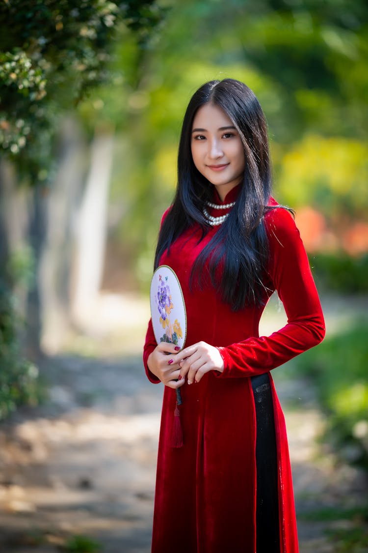 Smiling Asian Woman In Red Dress With Mirror In Park