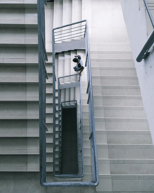 Free A person descending a modern staircase shot from an overhead angle, highlighting architectural design. Stock Photo
