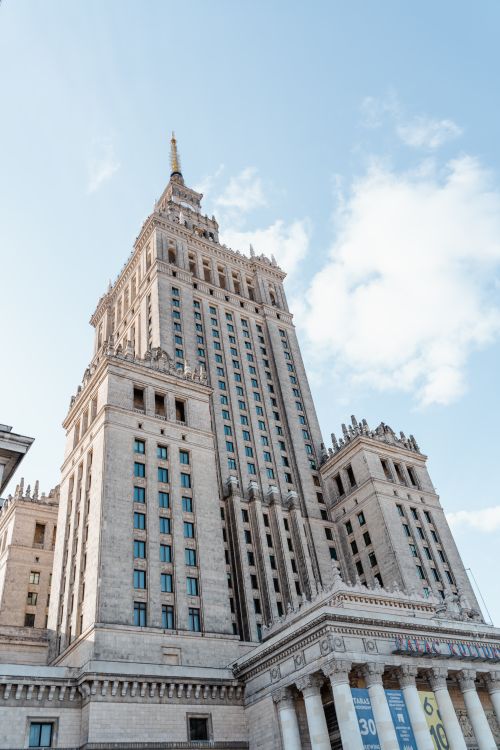 Free Low angle view of a neoclassical skyscraper with glass windows under blue skies. Stock Photo