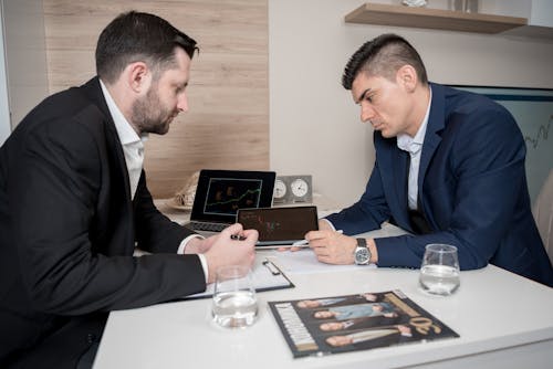 A Pair of Men in Suit Jackets Looking at a Graph on a Tablet