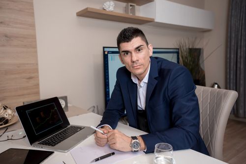 Free Businessman in blue suit working on laptop in sleek office setting, conveying professionalism and focus. Stock Photo