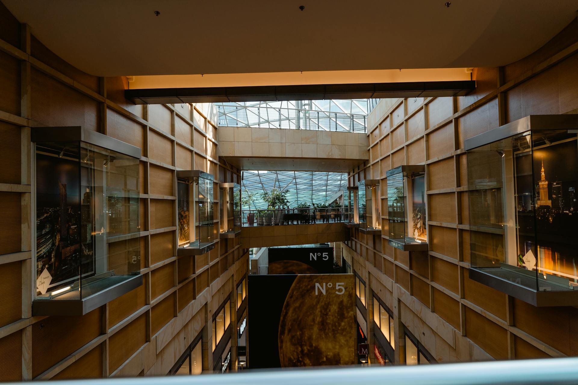 Bright indoor view of a modern shopping center with glass and wooden elements, showcasing urban design.