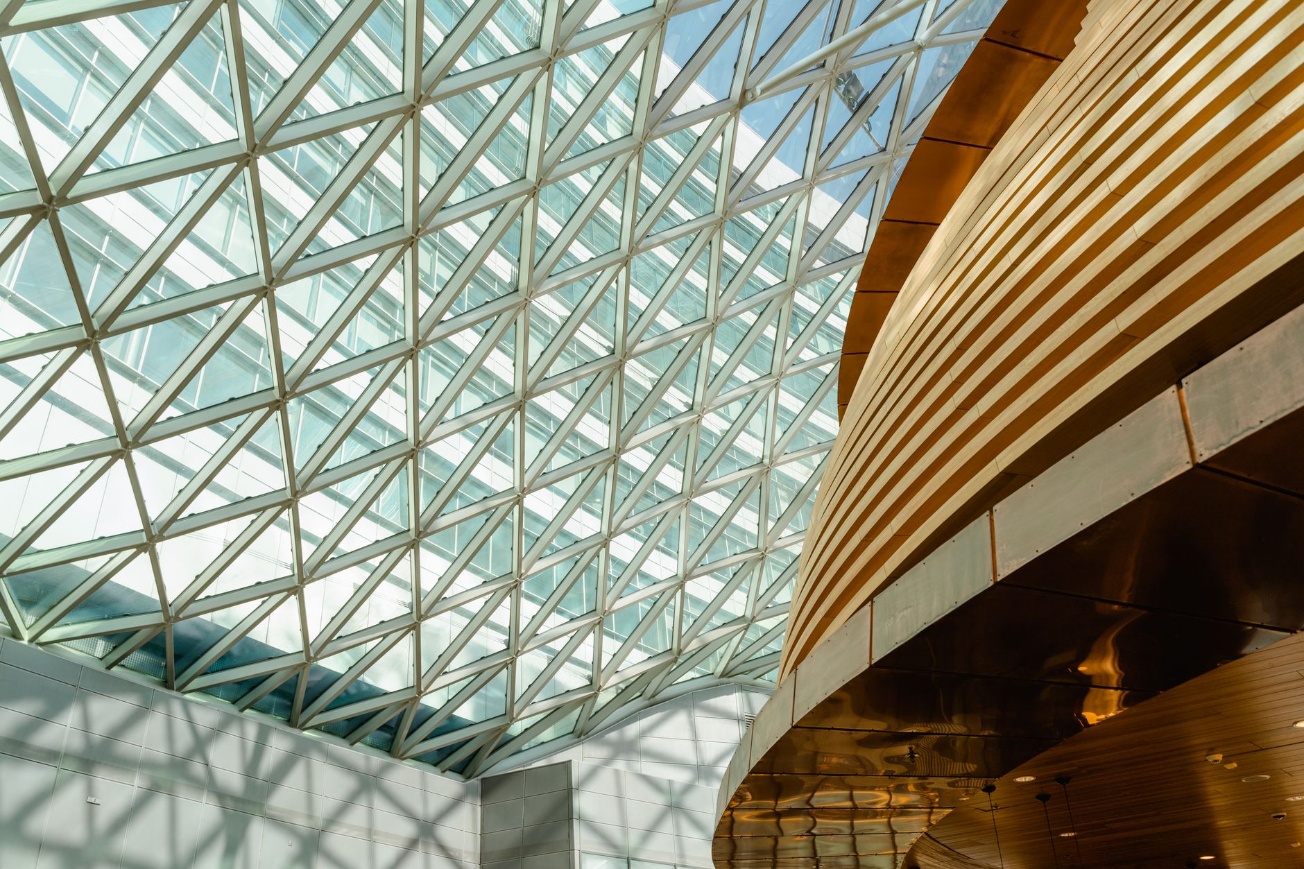 Modern architectural interior with a geometric glass ceiling and metal elements.