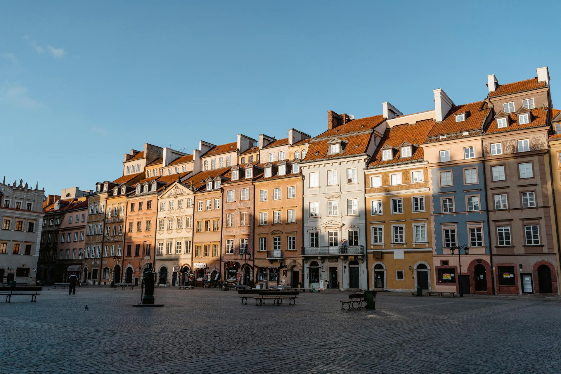 Picturesque view of Warsaw's Old Town square with colorful buildings under clear skies.