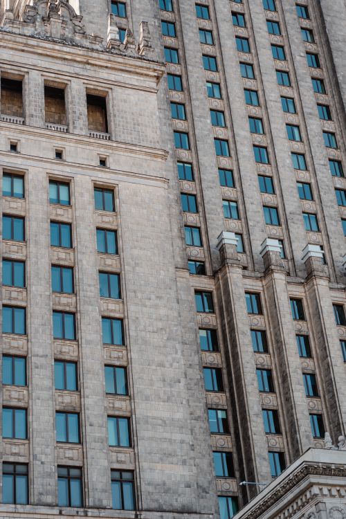 Free Close-up view of a neoclassical skyscraper facade with blue windows, showcasing architectural details. Stock Photo