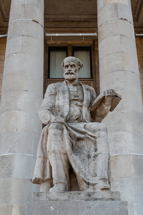 Stone Statue Of Man Holding A Book