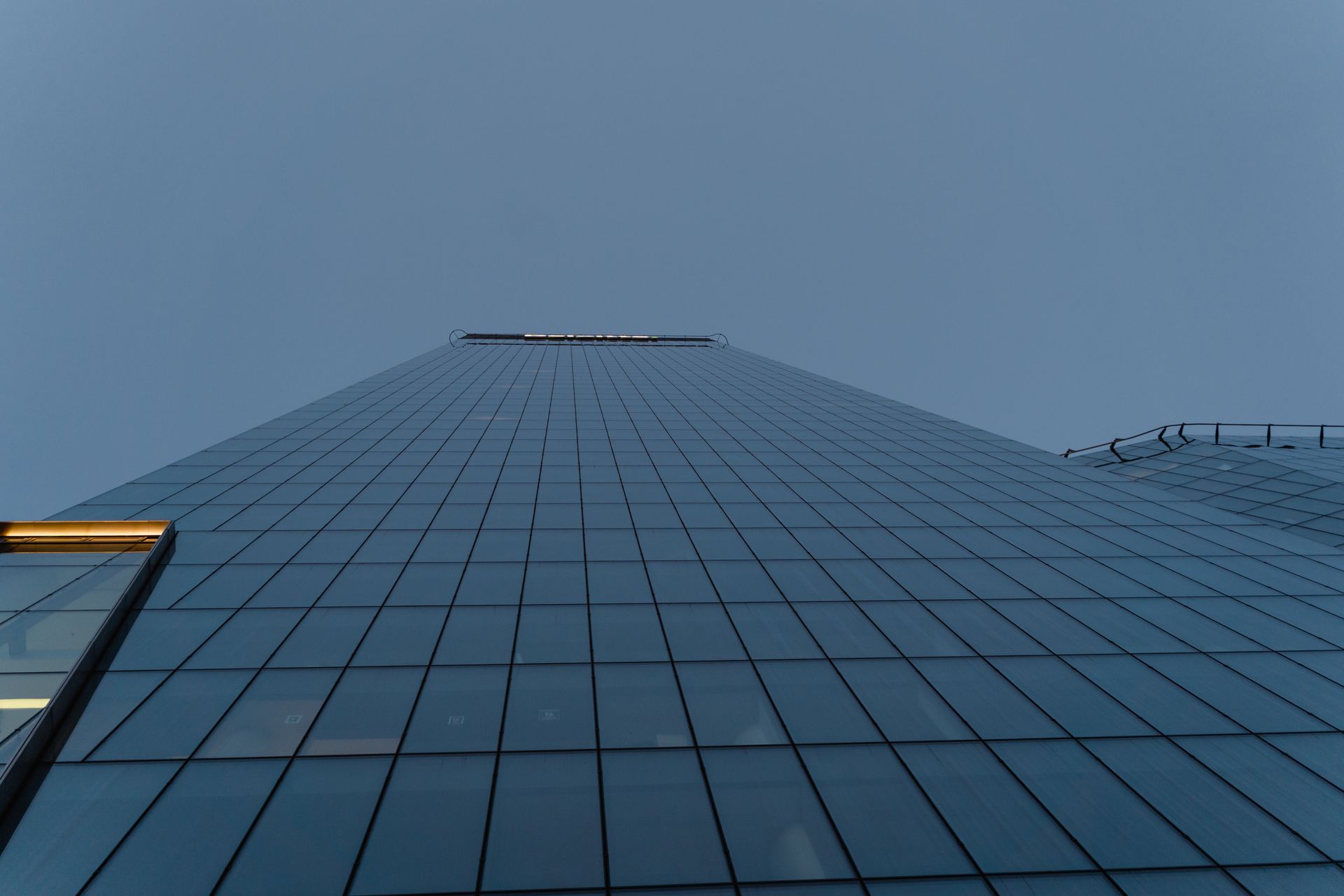 Stunning upward view of a modern skyscraper with reflective glass facade against clear blue sky.