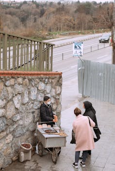 Street vendor in Istanbul selling food from a cart on a road with two customers.