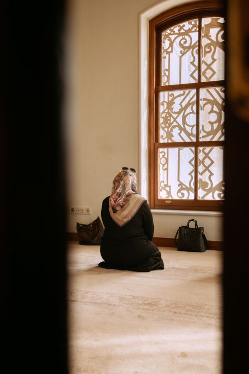 Free Rear view of a woman praying in a mosque, showcasing Islamic architecture and culture. Stock Photo