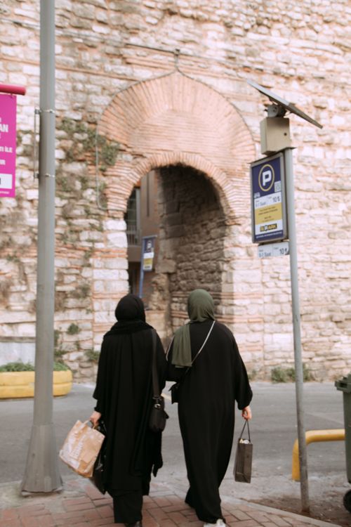 Free Two women in traditional clothing walking near ancient city walls in Istanbul. Stock Photo