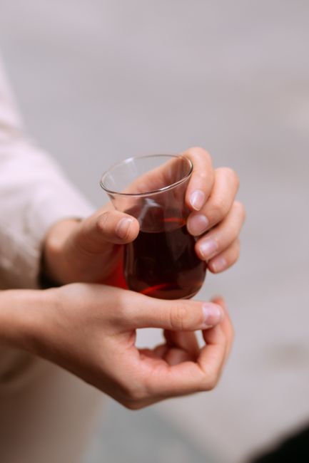Hands holding a traditional Turkish tea glass close-up. Perfect for lifestyle or cultural themes.