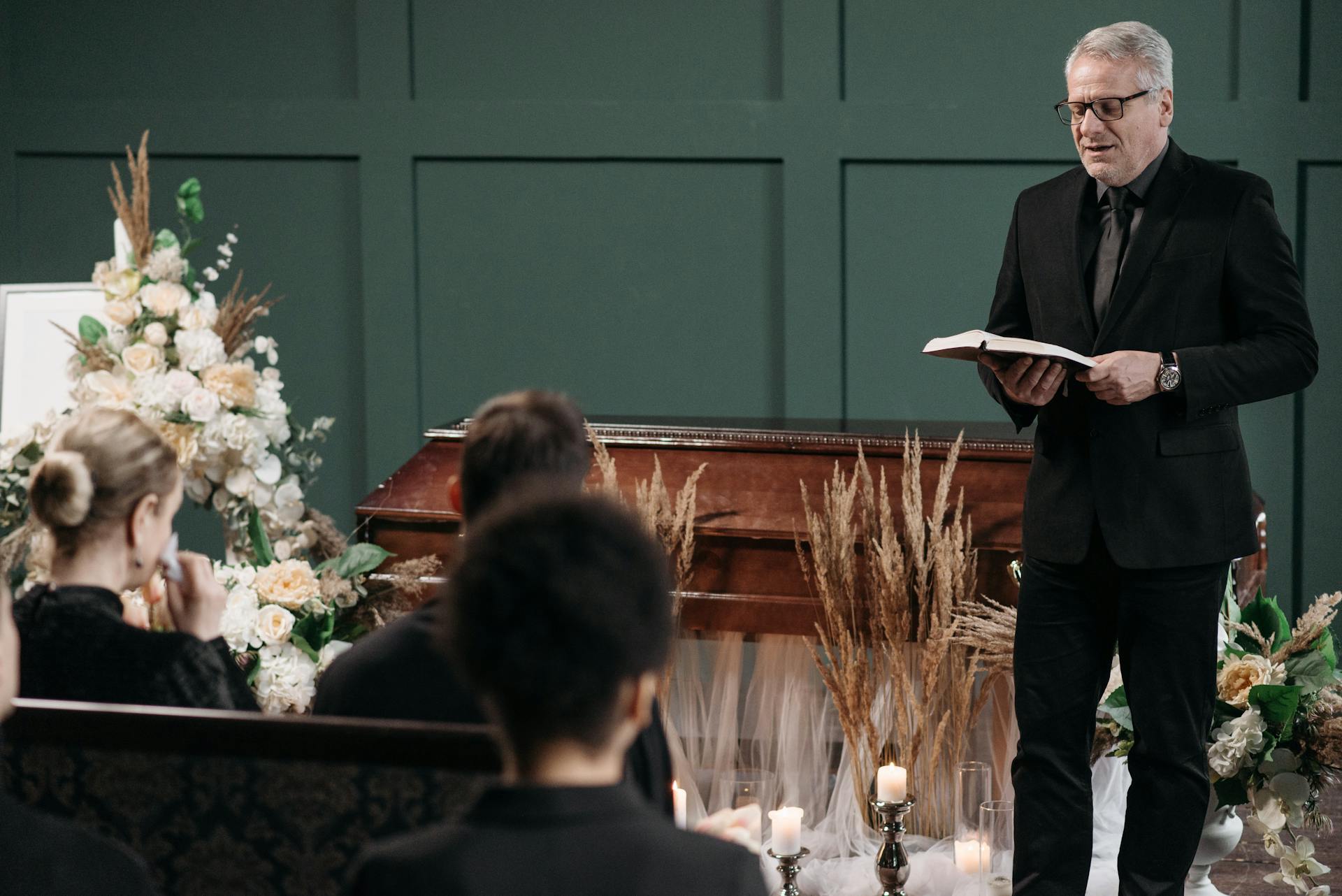 A Pastor Standing Beside a Coffin Conducting a Funeral Service