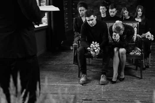 Black and white photo of a somber funeral ceremony with grieving individuals.