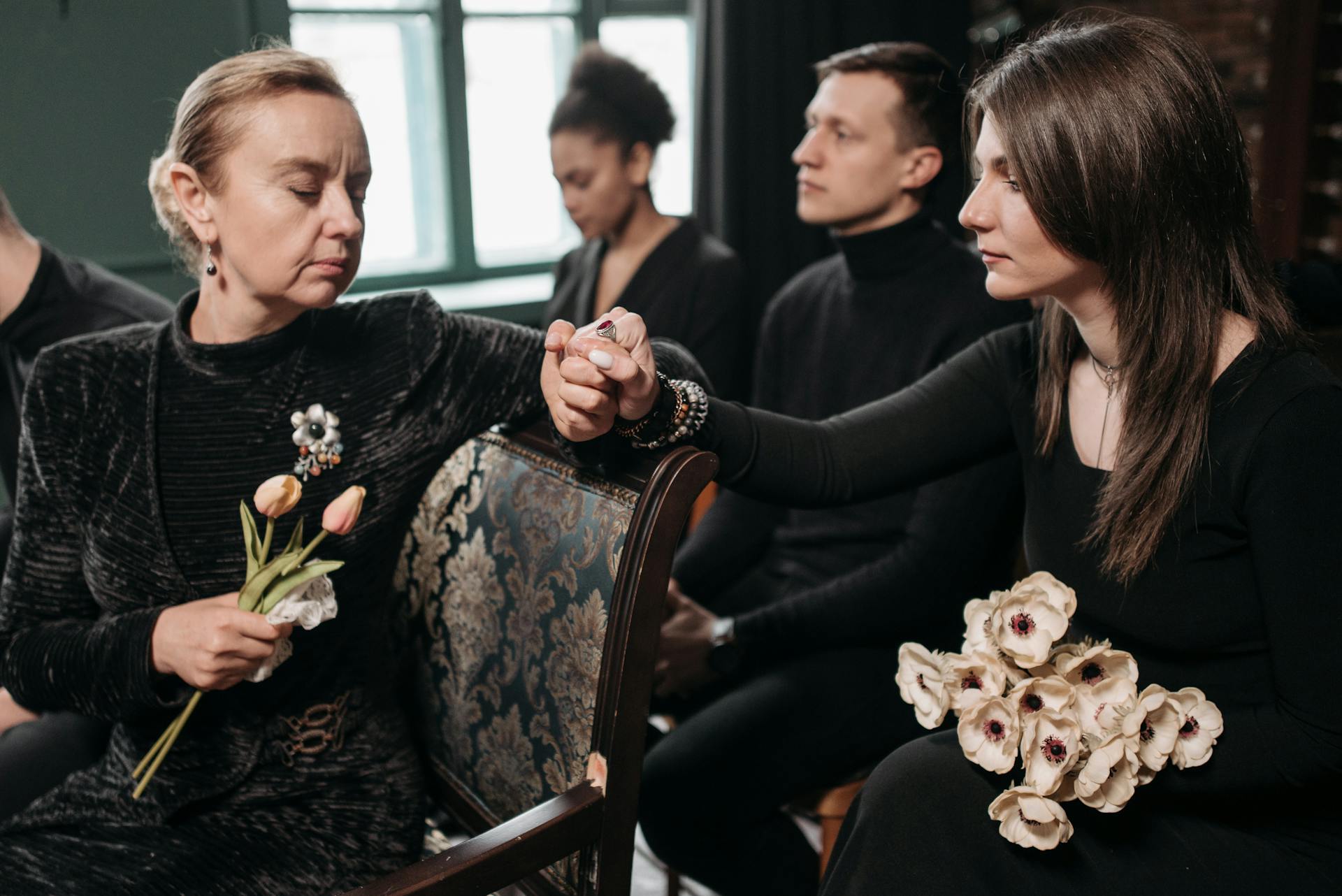 A somber family gathering indoors, displaying emotions of loss and support during a funeral.