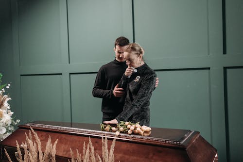 Free Man and Woman Standing Beside the Coffin Stock Photo