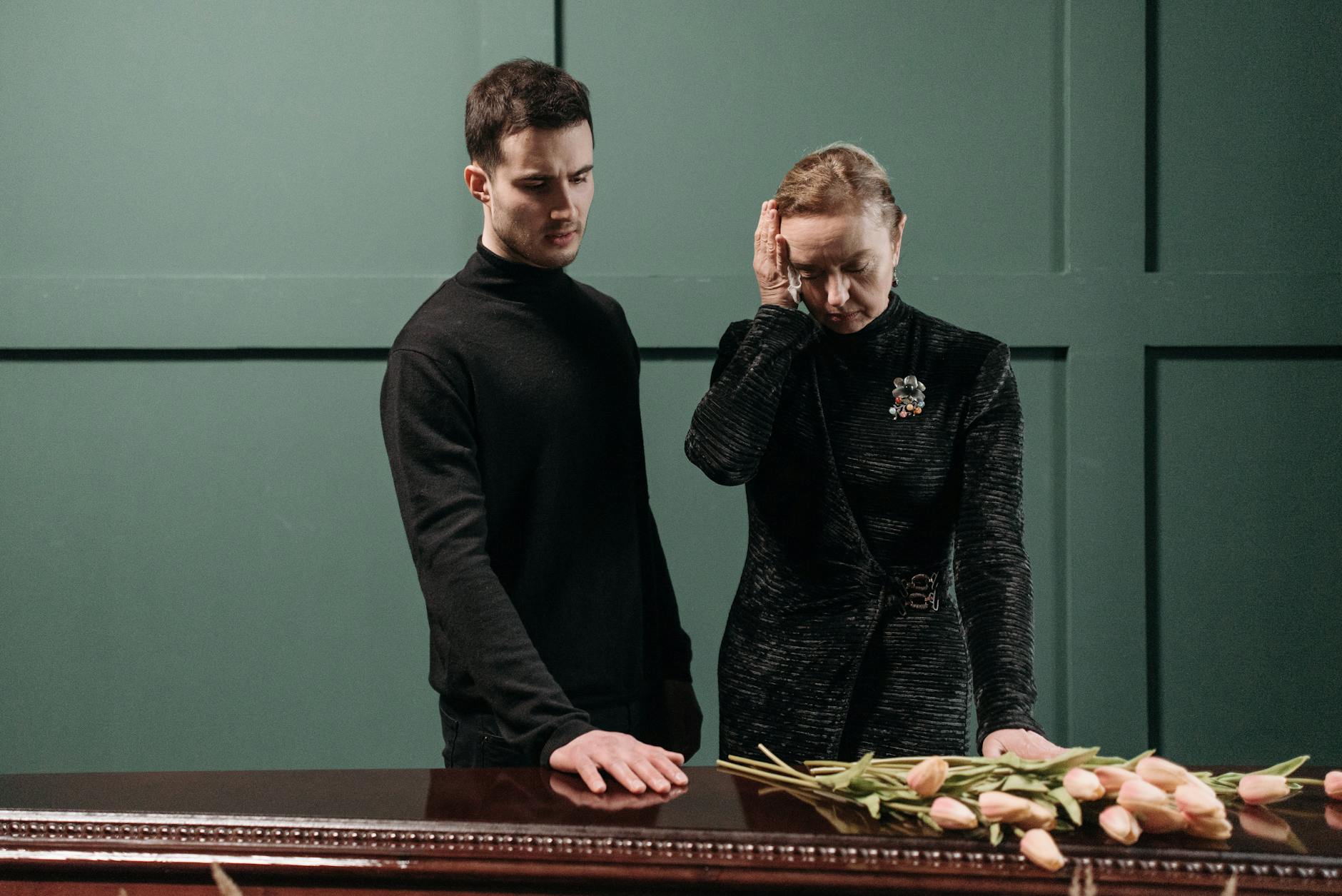 A Man and an Elderly woman Standing Near a Wooden Coffin