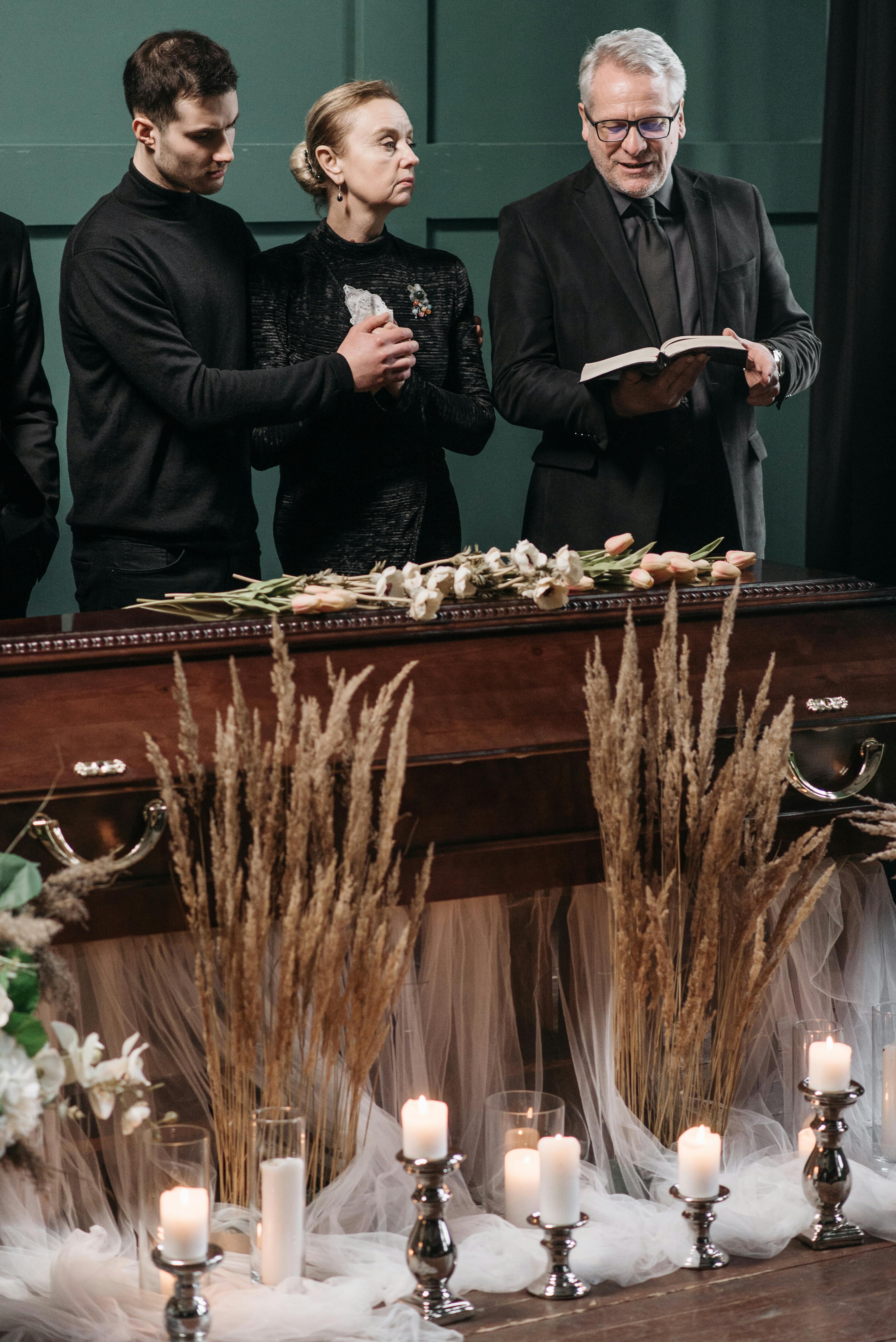 a woman standing between two men near a wooden coffin