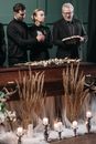 A Woman Standing Between Two Men Near a Wooden Coffin
