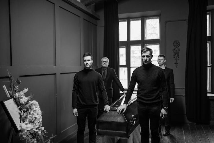 Group Of Men Standing Near A Wooden Coffin