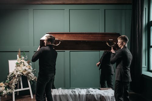 Free Group of Men Lifting a Wooden Coffin Stock Photo
