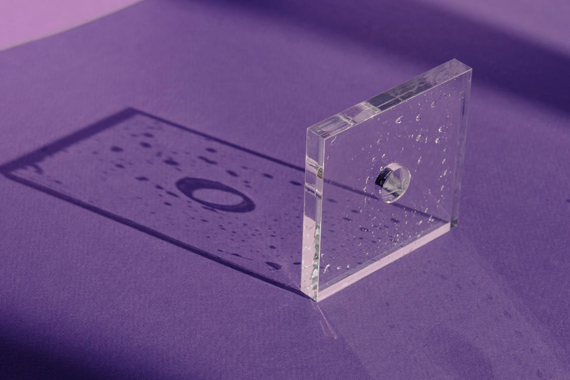 A Light Casting a Rectangular Shadow of a Square Glass with Water Droplets