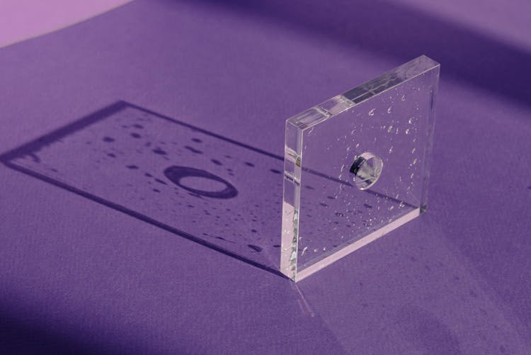 A Light Casting A Rectangular Shadow Of A Square Glass With Water Droplets