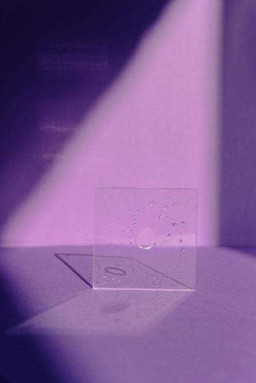 Free A conceptual image of a glass square with light, shadow, and reflections on a purple background. Stock Photo