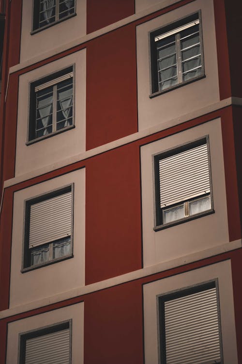 From below of facade of modern residential building with symmetric windows with shutters in city