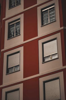 From below of facade of modern residential building with symmetric windows with shutters in city