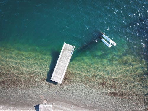 Floating pier in sea near sandy coast in sunlight