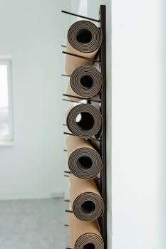 Close-up of neatly rolled yoga mats stored vertically on a rack in a studio.