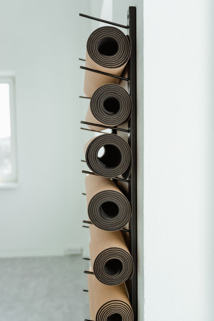 Rolled training mats stored on a studio wall rack — photo by MART PRODUCTION on Pexels