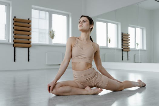 A young woman practices yoga in a bright, minimal studio setting, demonstrating a pigeon pose.