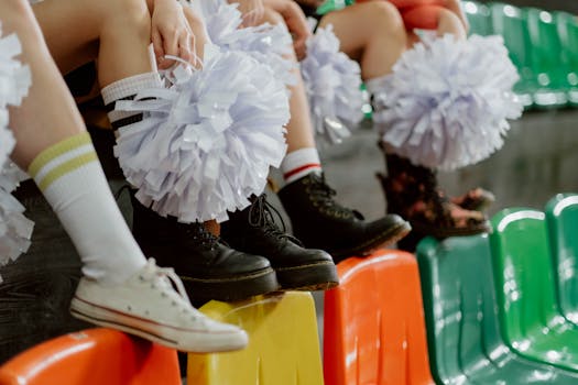 Dynamic close-up of cheerleaders' shoes and pompoms in vibrant seating area.
