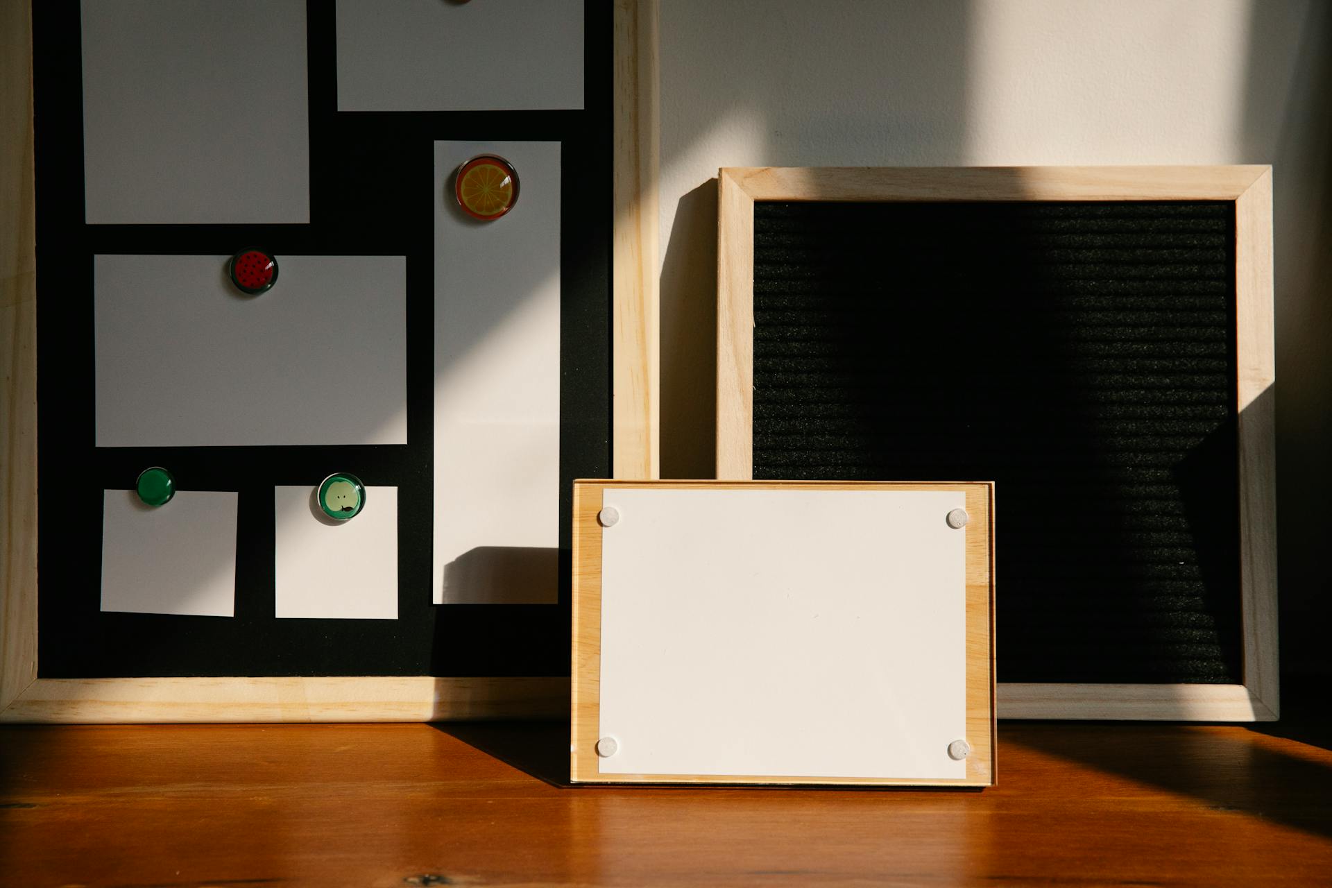 Three wooden-framed boards with magnets and placeholders on a wooden surface.