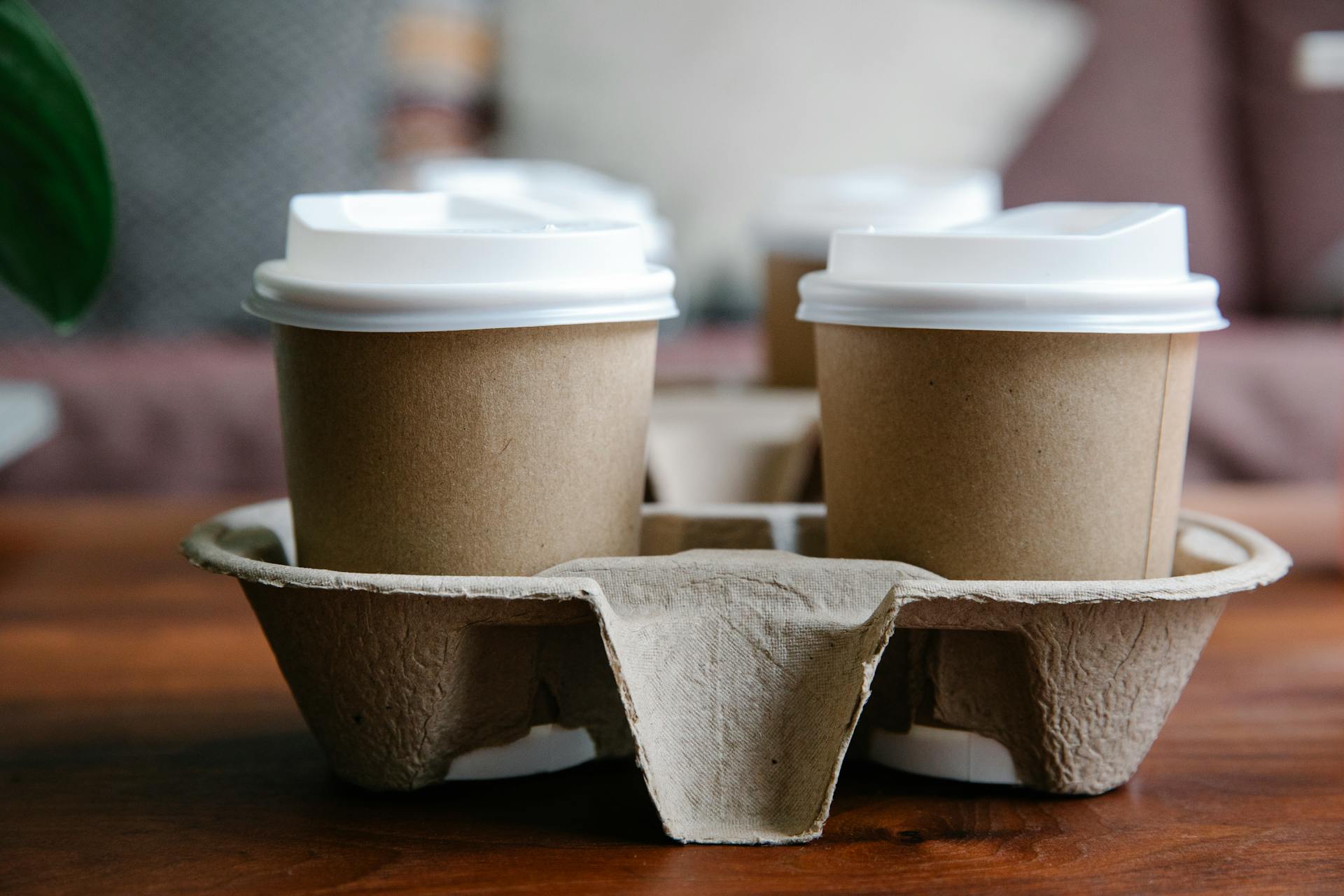 Close-up of eco-friendly disposable coffee cups in a cardboard holder, perfect for takeout or delivery.