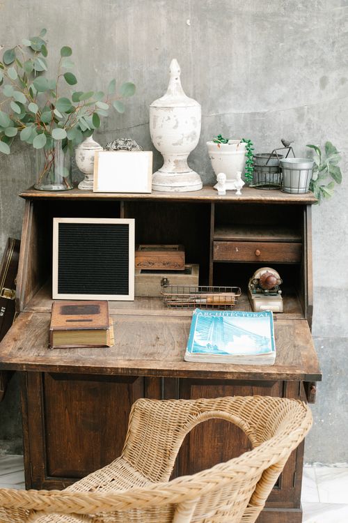 Free Rustic desk setup with decorative vases, books, and wicker chair. Stock Photo