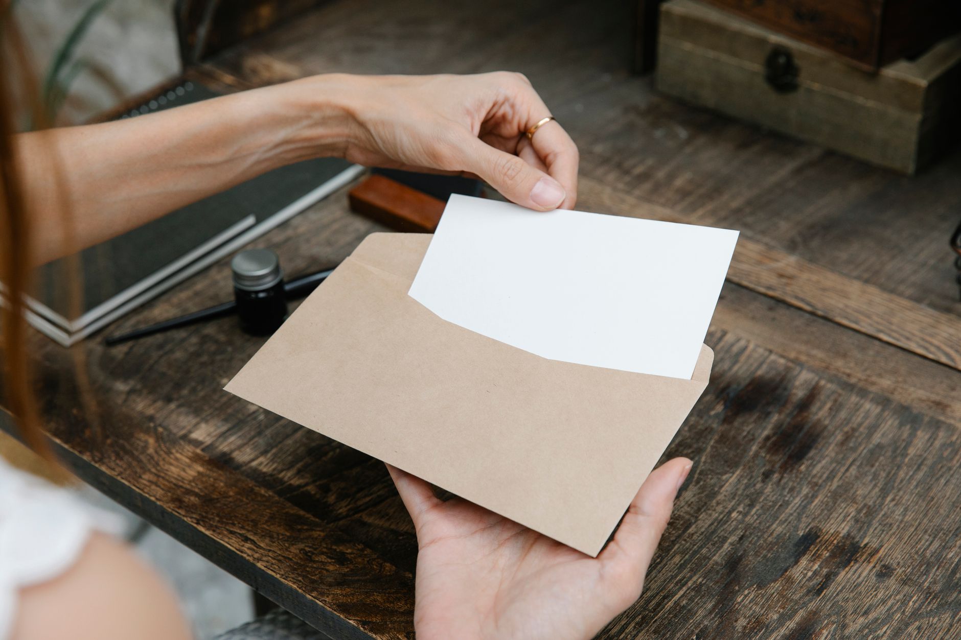 Hands holding an envelope and a card on a wooden desk, illustrating a gift that will need to be documented