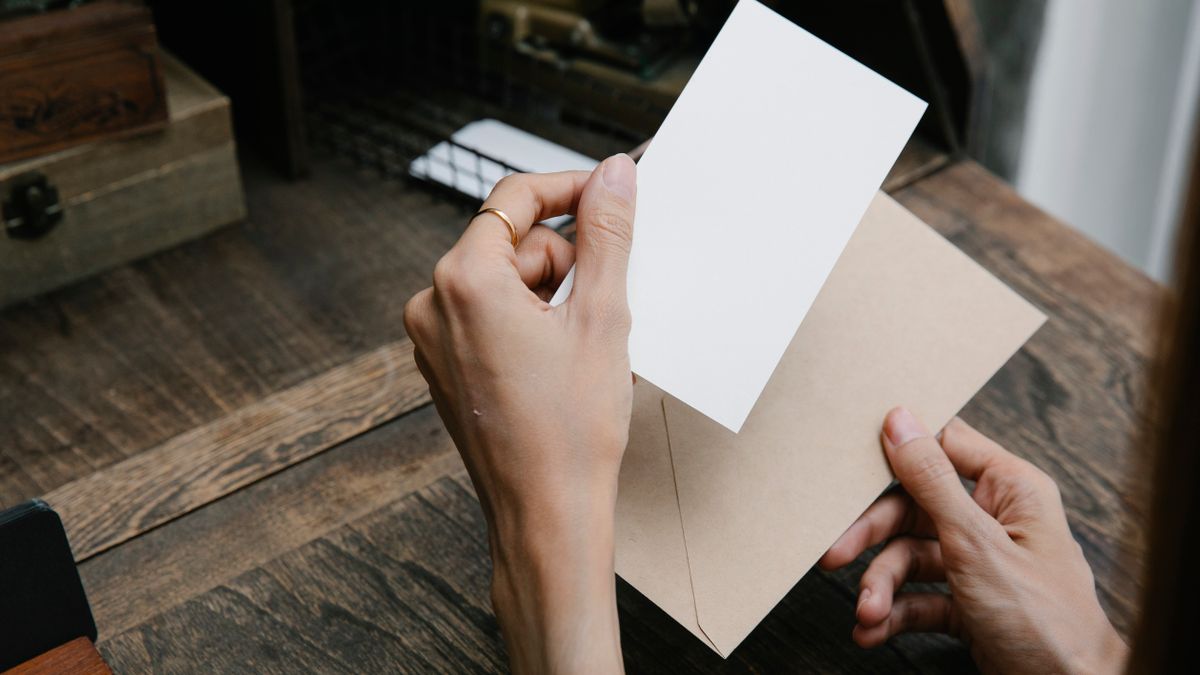 Hands holding an envelope and blank card, conveying simplicity and elegance.