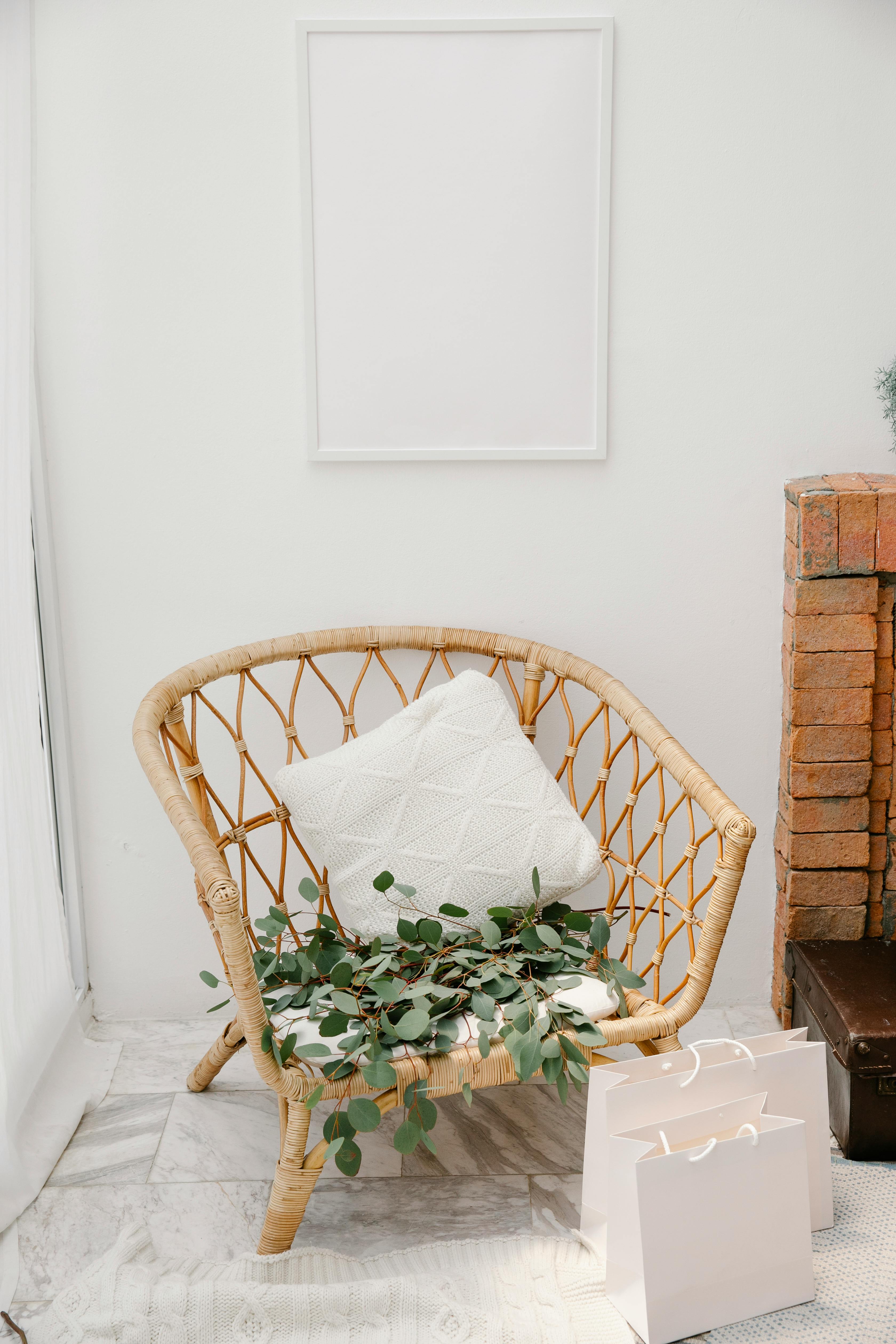 Free Minimalist setting with rattan chair, blank frame, and shopping bags. Stock Photo