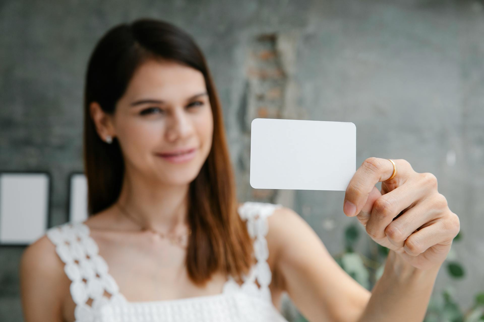 Young woman with long hair holding a blank card with a smile, perfect for business or personal branding.