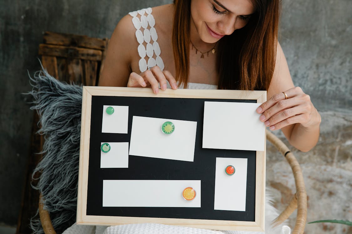 Free Woman Holding a Small Magnetic Board with Blank Pieces of Paper Stuck to It  Stock Photo