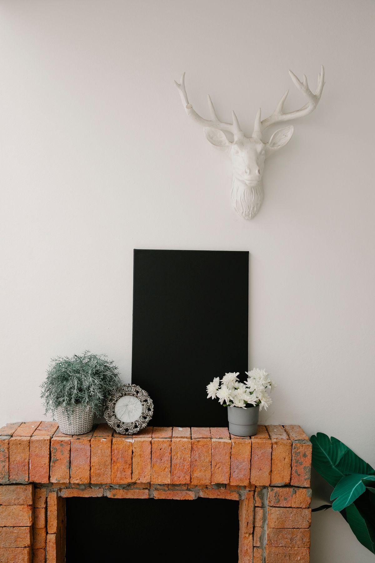 Stylish room with a faux deer head above a brick fireplace, contrasting modern decor elements. Stock Photo.